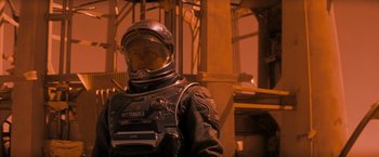 Movie still from “Red Planet” (2000), directed by Antony Hoffman – A man in a space suit standing in front of a metal structure; Medium shot, Over the shoulder angle