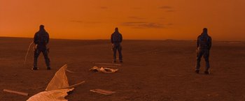 Movie still from “Red Planet” (2000), directed by Antony Hoffman – A man standing in the middle of an empty field; Extreme Wide shot, Over the shoulder angle