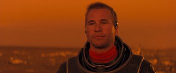 Movie still from “Red Planet” (2000), directed by Antony Hoffman – A man in a space suit is standing in front of a sunset; Close Up shot, Low angle