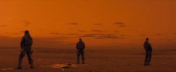 Movie still from “Red Planet” (2000), directed by Antony Hoffman – A man standing in the middle of an empty field; Extreme Wide shot, Low angle