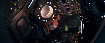 Movie still from “Red Planet” (2000), directed by Antony Hoffman – A woman sitting on a chair in a room with lights; Medium shot, High angle