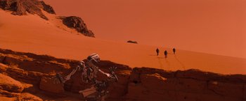 Movie still from “Red Planet” (2000), directed by Antony Hoffman – A group of people standing on top of a sandy hill; Extreme Wide shot, High angle