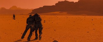 Movie still from “Red Planet” (2000), directed by Antony Hoffman – Two people walking on a dirt road in the desert; Wide shot, Low angle