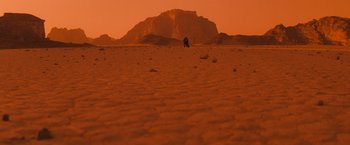 Movie still from “Red Planet” (2000), directed by Antony Hoffman – A person sitting in the middle of the desert; Extreme Wide shot, High angle