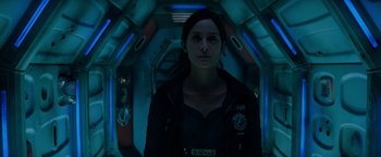 Movie still from “Red Planet” (2000), directed by Antony Hoffman – A woman standing inside of a room with lights on; Close Up shot, Overhead angle