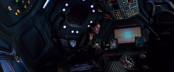 Movie still from “Red Planet” (2000), directed by Antony Hoffman – A woman sitting on a chair in a room; Wide shot, High angle