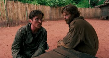 Movie still from “Rescue Dawn” (2006), directed by Werner Herzog – Two men are sitting at a table talking; Medium shot, Over the shoulder angle