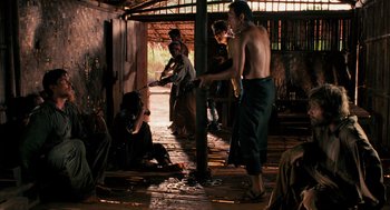 Movie still from “Rescue Dawn” (2006), directed by Werner Herzog – A group of people standing around in a room; Wide shot, Over the shoulder angle