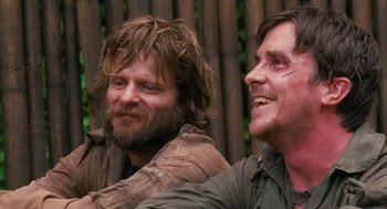 Movie still from “Rescue Dawn” (2006), directed by Werner Herzog – A couple of men sitting next to each other; Close Up shot, Low angle