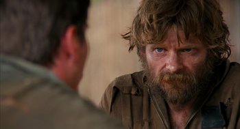 Movie still from “Rescue Dawn” (2006), directed by Werner Herzog – A man with long hair and a goatee stares at another man; Close Up shot, Over the shoulder angle