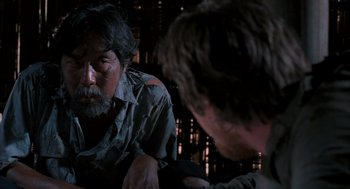 Movie still from “Rescue Dawn” (2006), directed by Werner Herzog – Two men are sitting in a dark room; Close Up shot, Over the shoulder angle