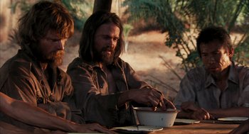 Movie still from “Rescue Dawn” (2006), directed by Werner Herzog – A man sitting at a table with a bowl of food in front of him; Medium shot, Over the shoulder angle
