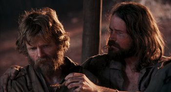 Movie still from “Rescue Dawn” (2006), directed by Werner Herzog – A man with long hair and a beard is holding a stick in his hand; Close Up shot, Over the shoulder angle