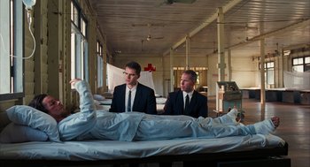Movie still from “Rescue Dawn” (2006), directed by Werner Herzog – Two men in suits sitting next to each other in a room; Wide shot, Low angle