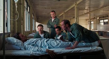 Movie still from “Rescue Dawn” (2006), directed by Werner Herzog – A group of men sitting on top of an unmade bed; Wide shot, Low angle