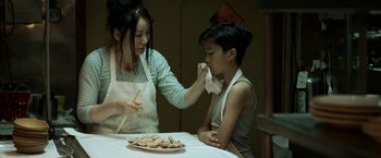 Movie still from “Revenge of the Green Dragons” (2014), directed by Andrew Loo – A woman and a boy sitting at a dinner table; Medium shot, Over the shoulder angle