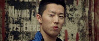 Movie still from “Revenge of the Green Dragons” (2014), directed by Andrew Loo – A person wearing a blue and black shirt; Close Up shot, Low angle