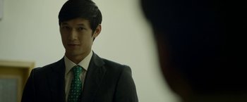 Movie still from “Revenge of the Green Dragons” (2014), directed by Andrew Loo – A man in a suit and a green tie; Close Up shot, Over the shoulder angle