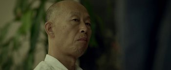Movie still from “Revenge of the Green Dragons” (2014), directed by Andrew Loo – An older man with a bald head looking to his left; Close Up shot, Low angle