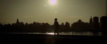 Movie still from “Revenge of the Green Dragons” (2014), directed by Andrew Loo – A person is walking on a bridge near the water; Wide shot, Low angle