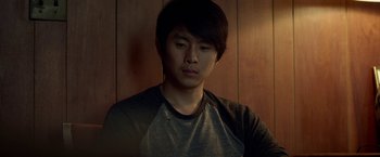 Movie still from “Revenge of the Green Dragons” (2014), directed by Andrew Loo – A young man in a gray and black t - shirt; Close Up shot, High angle
