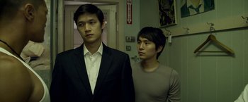 Movie still from “Revenge of the Green Dragons” (2014), directed by Andrew Loo – Two men standing next to each other in front of a door; Medium shot, Over the shoulder angle