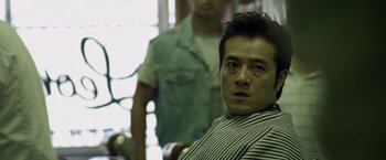 Movie still from “Revenge of the Green Dragons” (2014), directed by Andrew Loo – A person sitting in front of another person; Close Up shot, Over the shoulder angle