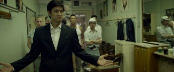 Movie still from “Revenge of the Green Dragons” (2014), directed by Andrew Loo – A group of men standing in a room; Medium shot, Over the shoulder angle