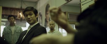 Movie still from “Revenge of the Green Dragons” (2014), directed by Andrew Loo – A man in a black suit is looking at another man in a white shirt; Close Up shot, Over the shoulder angle