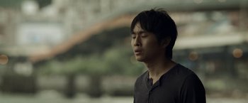 Movie still from “Revenge of the Green Dragons” (2014), directed by Andrew Loo – A young asian man with his eyes closed; Close Up shot, Low angle
