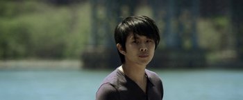 Movie still from “Revenge of the Green Dragons” (2014), directed by Andrew Loo – A young man with black hair is looking at the camera; Close Up shot, Low angle
