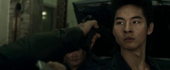 Movie still from “Revenge of the Green Dragons” (2014), directed by Andrew Loo – A man holding a gun in front of another man; Close Up shot, Over the shoulder angle