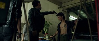 Movie still from “Revenge of the Green Dragons” (2014), directed by Andrew Loo – A man is holding a gun and another man is holding a knife; Medium shot, Over the shoulder angle