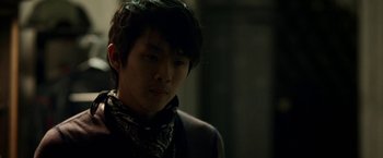 Movie still from “Revenge of the Green Dragons” (2014), directed by Andrew Loo – A young man with long black hair wearing a neck tie; Close Up shot, Over the shoulder angle
