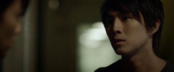 Movie still from “Revenge of the Green Dragons” (2014), directed by Andrew Loo – A person's face in a dark room; Close Up shot, Low angle