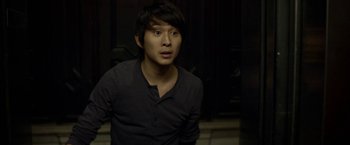 Movie still from “Revenge of the Green Dragons” (2014), directed by Andrew Loo – A young man in a black shirt is looking at the camera; Close Up shot, High angle