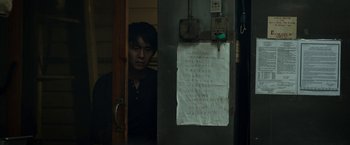 Movie still from “Revenge of the Green Dragons” (2014), directed by Andrew Loo – A man standing in front of an open door; Medium shot, Low angle