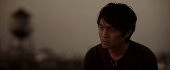 Movie still from “Revenge of the Green Dragons” (2014), directed by Andrew Loo – A man sitting in front of a window looking off into the distance; Close Up shot, Low angle