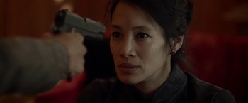 Movie still from “Revenge of the Green Dragons” (2014), directed by Andrew Loo – A woman holding a gun up to her face; Close Up shot, Over the shoulder angle