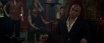 Movie still from “Revenge of the Green Dragons” (2014), directed by Andrew Loo – A group of men sitting in a room with a glass of wine; Medium shot, Over the shoulder angle
