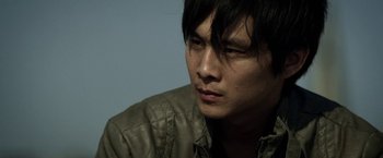 Movie still from “Revenge of the Green Dragons” (2014), directed by Andrew Loo – A person wearing a leather jacket; Close Up shot, Low angle