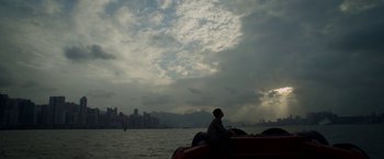 Movie still from “Revenge of the Green Dragons” (2014), directed by Andrew Loo – A man sitting in a boat on a body of water; Extreme Wide shot, Low angle