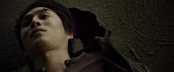 Movie still from “Revenge of the Green Dragons” (2014), directed by Andrew Loo – A man laying on the ground with a black shirt on; Extreme Close Up shot, Overhead angle