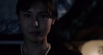 Movie still from “Ringu” (1998), directed by Hideo Nakata – A woman with a pearl necklace is posing for a picture; Close Up shot, Low angle
