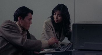 Movie still from “Ringu” (1998), directed by Hideo Nakata – A man and a woman working together on a laptop computer; Medium shot, High angle