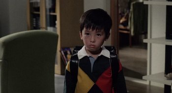 Movie still from “Ringu” (1998), directed by Hideo Nakata – A young boy wearing a backpack in a living room; Medium shot, High angle