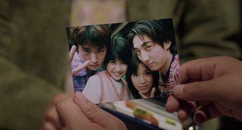 Movie still from “Ringu” (1998), directed by Hideo Nakata – A person holding a picture of a group of young people; Extreme Close Up shot, High angle