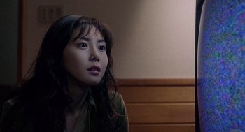 Movie still from “Ringu” (1998), directed by Hideo Nakata – A woman sitting in front of a wooden wall looking up; Close Up shot, High angle