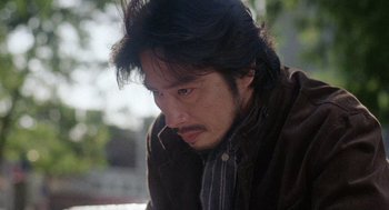 Movie still from “Ringu” (1998), directed by Hideo Nakata – A person wearing a brown jacket; Close Up shot, Low angle