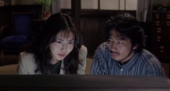 Movie still from “Ringu” (1998), directed by Hideo Nakata – A man and a woman looking at a computer screen; Medium shot, High angle